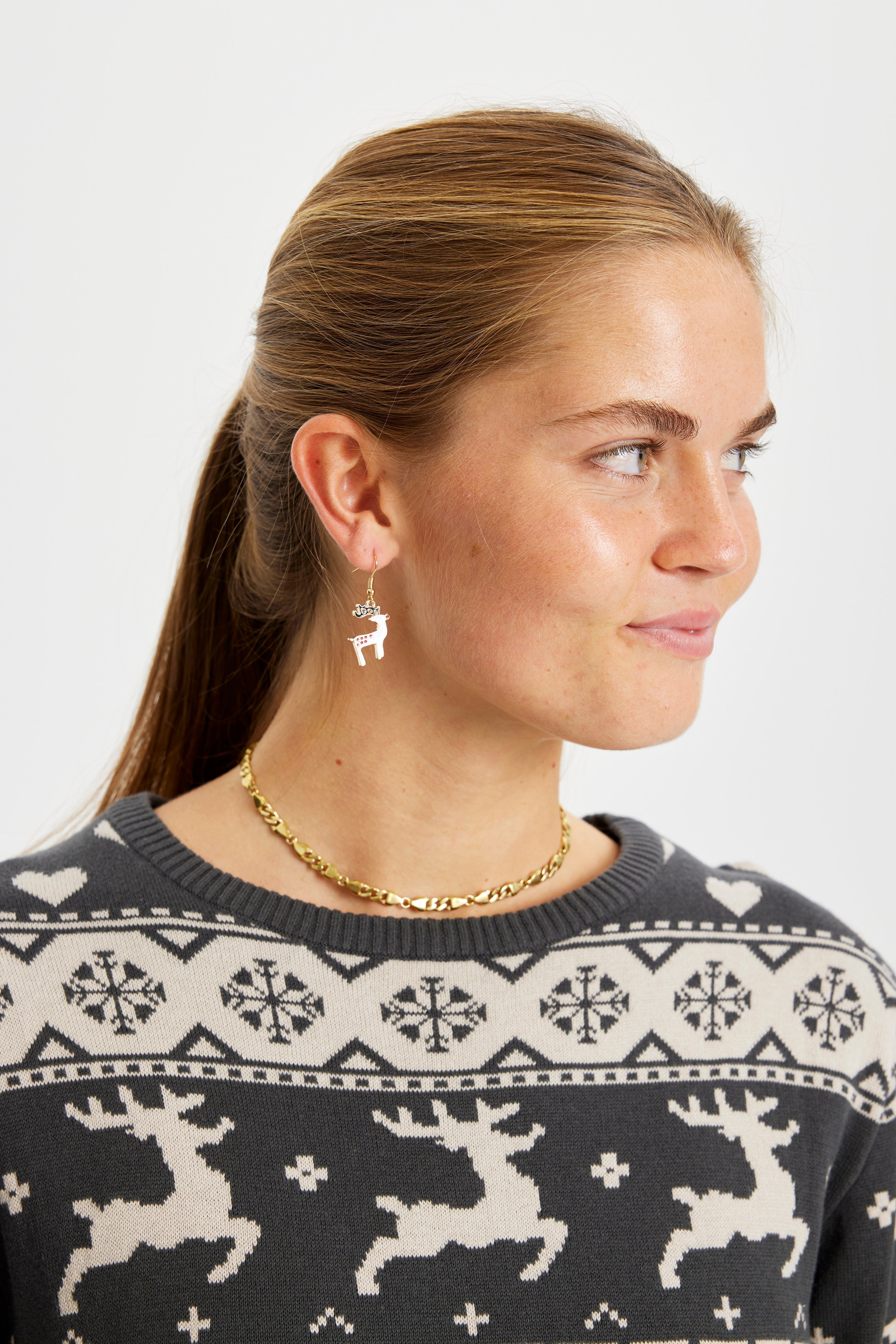 Een vrouw draagt kerstoorbellen die op rendieren lijken.